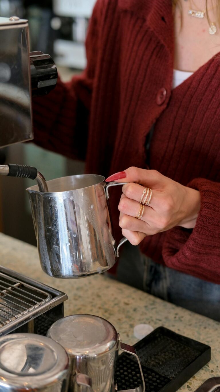 Barista steaming milk at espresso machine in cozy cafe setting.