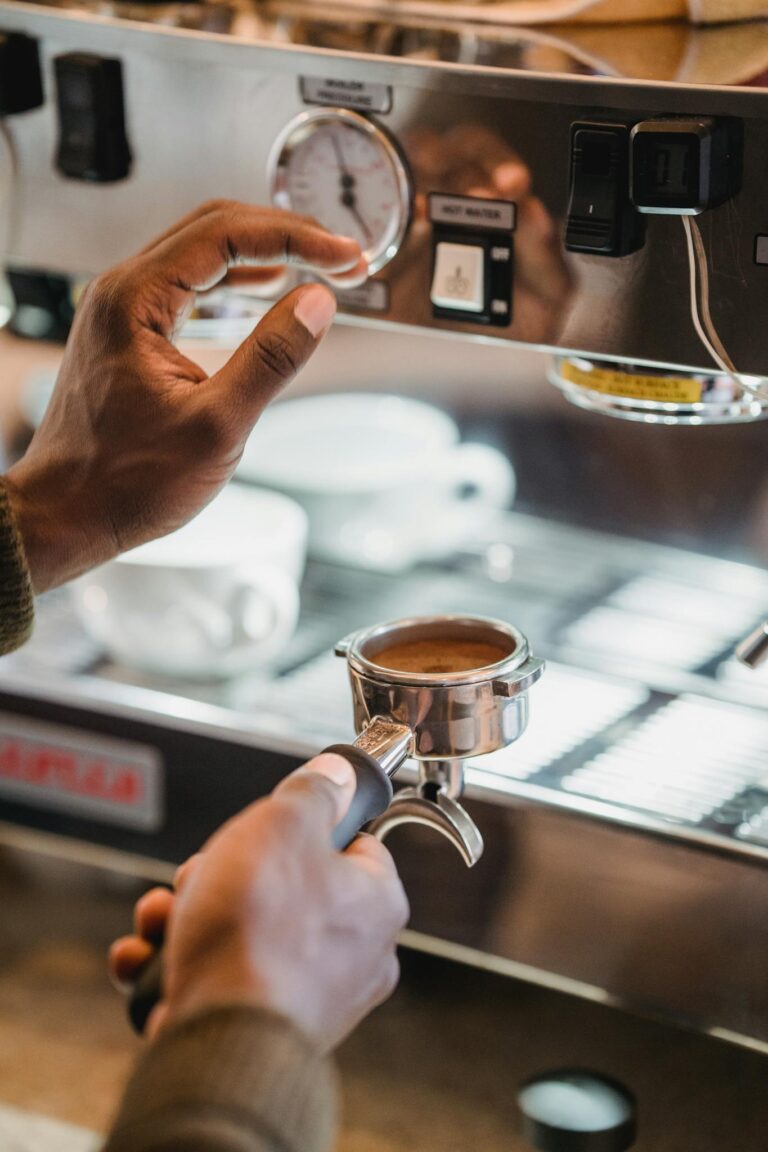 Person adjusting espresso machine with a coffee portafilter in focus.