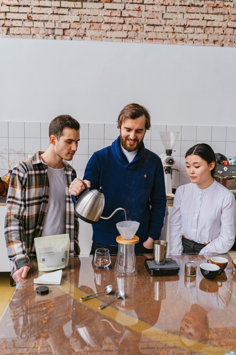 Three adults engaged in a coffee brewing workshop, mastering pour-over techniques in a cozy café setting.